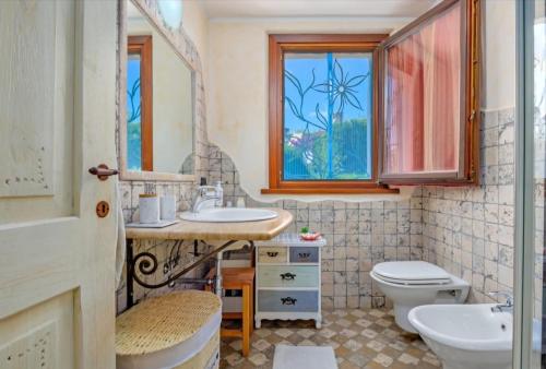 a bathroom with a sink and a toilet and a window at Appartamento pittulongu in Olbia