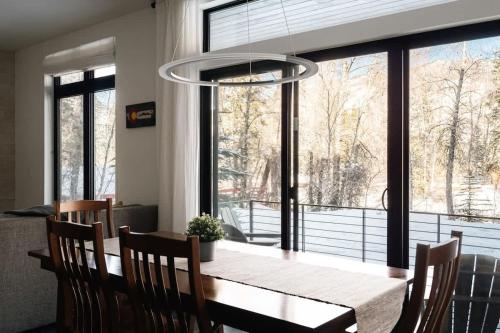 a dining room table with chairs and a large window at Riverfront Patio - Hot Tub - Luxe Silverthorne in Silverthorne