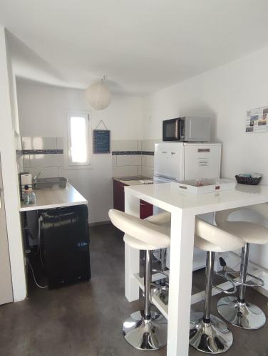 - une cuisine avec une table blanche et des chaises dans l'établissement Mas Boucard Terrasse et parking privés, à Frontignan