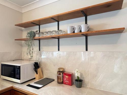 a kitchen with a counter with a microwave and shelves at Cute Cottage Home - Vintage Charm & Great Location at Slacks Creek, Close to Logan Central & M1 in Slacks Creek
