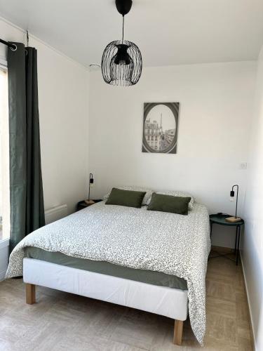 a white bedroom with a bed and a chandelier at Maison familiale et chaleureuse à la chaume av 2 chambres, terrasse, wifi in Les Sables-dʼOlonne
