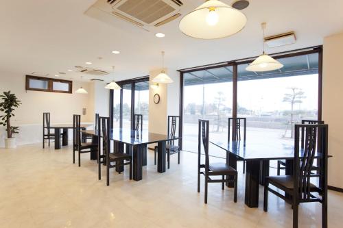 une salle à manger avec des tables et des chaises ainsi qu'une grande fenêtre dans l'établissement Athena Kaigetsu, à Awaji
