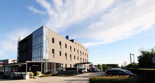 a building with cars parked in a parking lot at Best Western Airport Hotel Stella in Zagreb