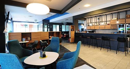 a restaurant with blue chairs and tables and a bar at Best Western Airport Hotel Stella in Zagreb