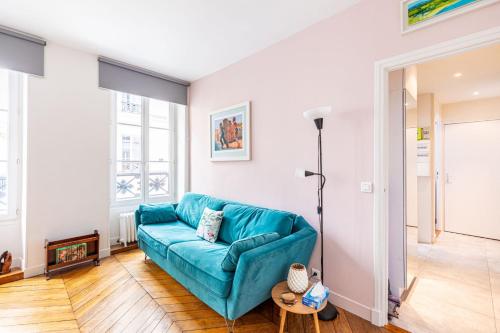 un salon avec un canapé bleu et une table dans l'établissement GuestReady - A lovely stay in Batignolles, à Paris