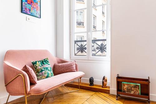 un salon avec une chaise rose et une fenêtre dans l'établissement GuestReady - A lovely stay in Batignolles, à Paris