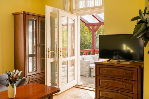 a living room with a tv and a sliding glass door at Villa Emausy in Luhačovice
