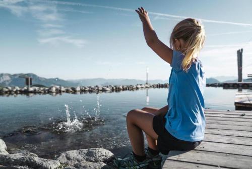 a young girl is sitting on a dock near the water at Denggnhof in Münster