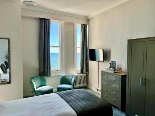 a hotel room with a bed and two chairs at The Cumberland Hotel in Eastbourne