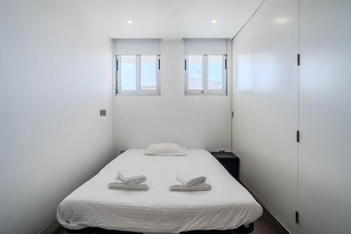 a white room with a bed with two slippers on it at H2O Apartment - Rooftop with pool in Santa Cruz in Santa Cruz