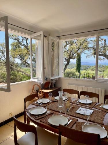 une salle à manger avec une table, des chaises et des fenêtres dans l'établissement Villa Provençale Vue Mer, à Bormes-les-Mimosas