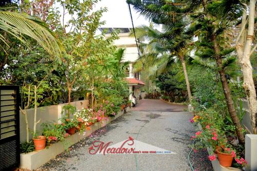 a garden path with flowers and palm trees at Meadows Serene Retreat in Kannur
