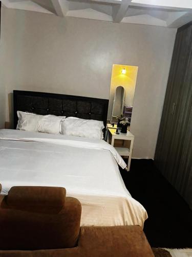 a bedroom with a large white bed and a mirror at Tulivu Apartment in Nairobi