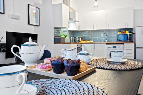 a kitchen with a table with cups and pastries on it at Spacious Family Apartment, Sleeps 6, FREE Secure Parking, Near Beach in Bournemouth