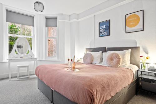 a bedroom with a large bed with a pink bedspread at Spacious one bed Apartment, contractor friendly, Sleeps 6, FREE Secure Parking, Near Beach in Bournemouth
