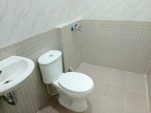 a bathroom with a white toilet and a sink at Bebek Kuning Residence in Blimbing
