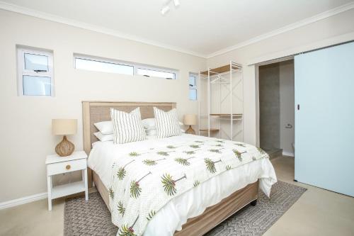 a bedroom with a bed with a white bedspread with palm trees at Casa Azul Downstairs Apartment in Struisbaai