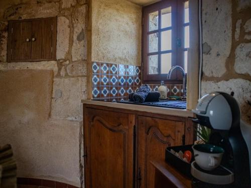 une cuisine avec un évier et une fenêtre dans l'établissement Moulin à vent restauré et classé meublé de tourisme, à Roquecor