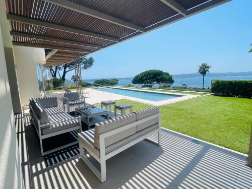 un patio avec une table et des chaises et une piscine dans l'établissement Villa MireMer - Vue panoramique face au Golfe de Saint-Tropez, à Sainte-Maxime