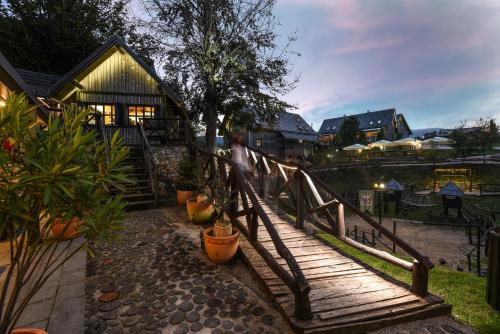 a person walking over a wooden bridge in front of a house at Lakeside Hotel Plitvice in Plitvička Jezera