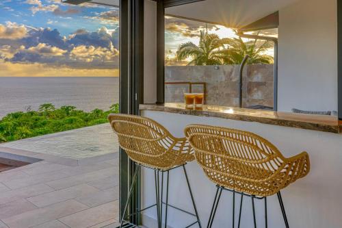 two chairs sitting at a bar with a view of the ocean at Villa Panorama Grand Anse in Petite Île
