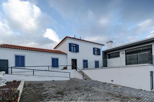 a white house with blue windows and stairs at Casa do Músico in Alverca