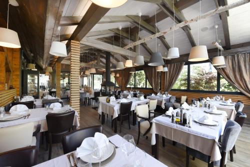 a restaurant with white tables and chairs and large windows at Lakeside Hotel Plitvice in Plitvička Jezera