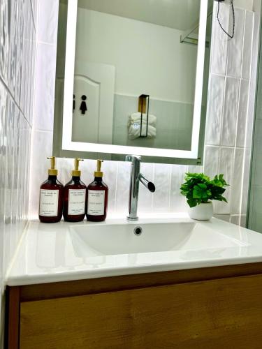 a bathroom sink with three bottles of wine on it at Studio à 1 min de la plage ! in Sainte-Luce