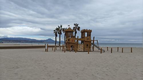 a playground on a beach with palm trees and the ocean at Playa y montaña 1ª linea Piscina Parking AC in El Campello