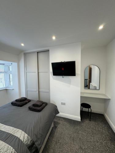 a bedroom with a bed and a tv on the wall at The Crescent-Modern Coastal Home in Blackpool