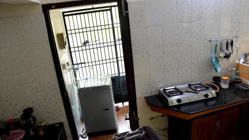 a kitchen with a stove and a door leading into a kitchen at Meadows Serene Retreat in Kannur