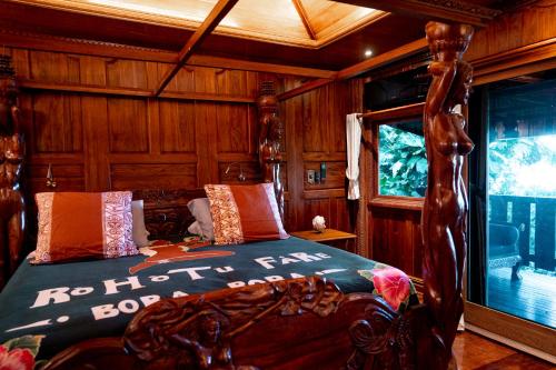 a bedroom with a bed with a wooden wall at Rohotu Fare in Bora Bora