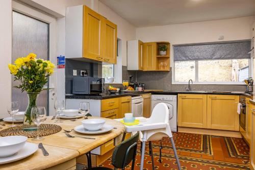 a kitchen with a wooden table with a vase of flowers at Motorpoint Arena House - Sleeps 10 in Nottingham
