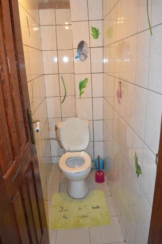 a bathroom with a toilet with a rug on the floor at Résidence Hotelière Borel Denver in Douala