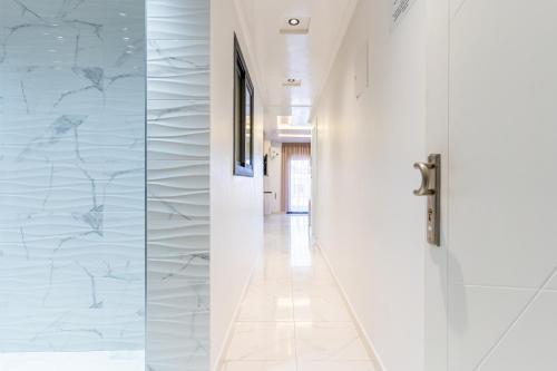 a hallway with white marble walls and a door at Hot appar Luxury SuiteMar in M'diq