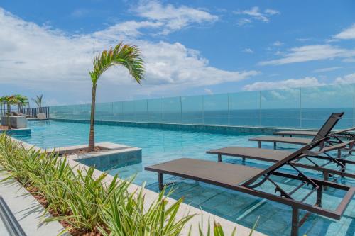 a swimming pool with tables and a palm tree at ArtStudio Open Spaces in Salvador