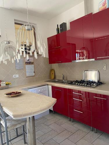 una cucina con armadi rossi e un tavolo di La Voce della Natura a Fermo