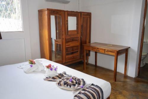 a room with two beds and a table and a dresser at Nuestra Casa in San Juan del Sur