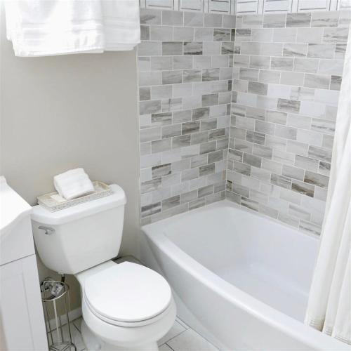 a bathroom with a white toilet and a tub and a sink at Exclusive Apt in Shaw in Washington, D.C.