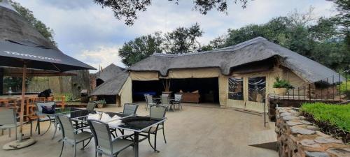 eine Terrasse mit Stühlen und Tischen und ein Gebäude in der Unterkunft Tidimalo Lodge in Rustenburg