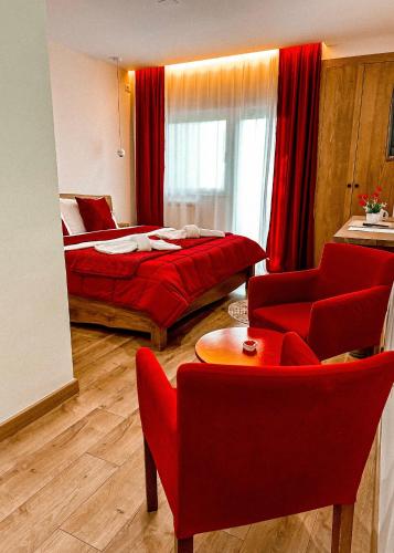 a bedroom with a red bed and a red chair at Vila Alpini in Razëm