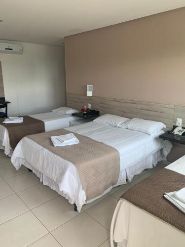 a hotel room with three beds in a room at Hotel La Ville in Sousa
