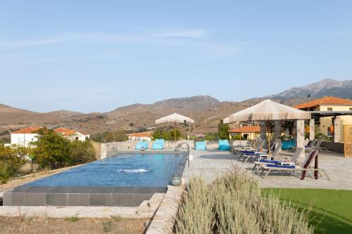 a pool with chairs and umbrellas in a resort at Lampetos Houses Molyvos in Mithymna