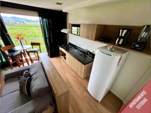 a kitchen with a refrigerator and a table with a view at Verano Stay Flat Barra Olímpica in Rio de Janeiro