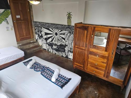 a room with two beds and a wooden cabinet at Nuestra Casa in San Juan del Sur