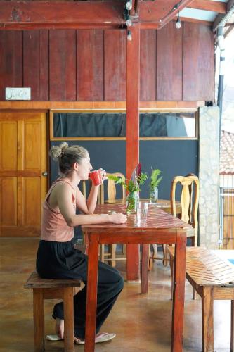 a woman sitting at a table drinking from a red cup at Nuestra Casa in San Juan del Sur