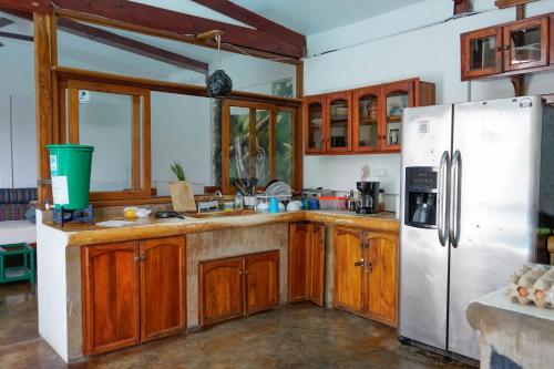 a kitchen with wooden cabinets and a white refrigerator at Nuestra Casa in San Juan del Sur