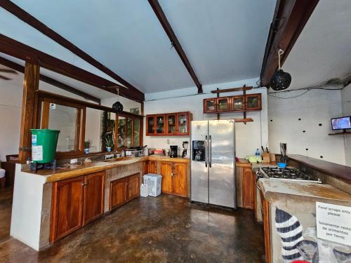 a kitchen with wooden cabinets and a stainless steel refrigerator at Nuestra Casa in San Juan del Sur