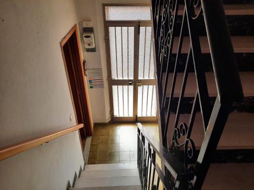 a hallway with a stairway with a door and a stair railing at Domu Asquer 5 in Fluminimaggiore