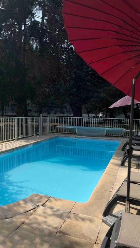 - une piscine bleue avec un parasol rouge dans l'établissement Studio Saint-Lary Soulan village, à Saint-Lary-Soulan